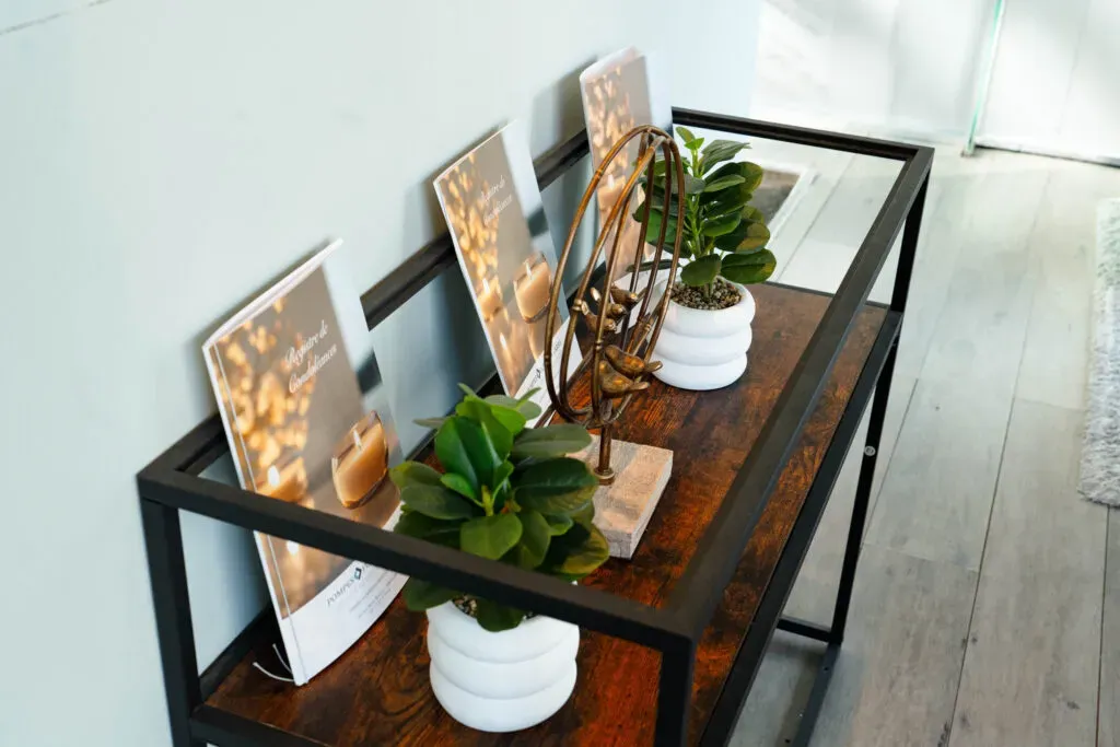 Console décorative en bois et métal avec plantes et registres de condoléances.